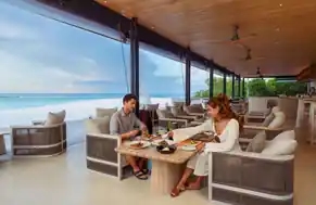 A tropical cocktail with an orange slice on top, set against the beautiful backdrop of Maldives.