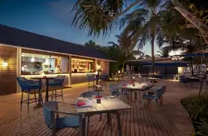 A man stands behind a bar, showcasing a variety of bottles.
